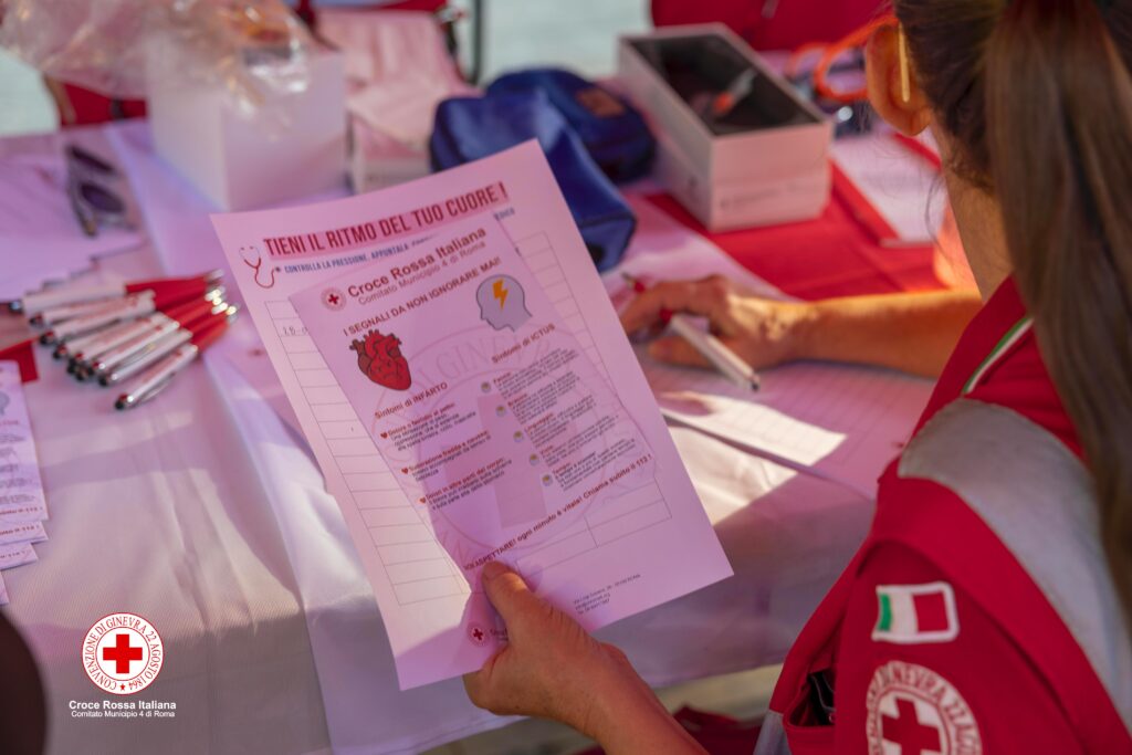 Volontaria della Croce Rossa Italiana mostra un volantino sui segnali da non ignorare per infarto e ictus durante la Giornata Mondiale del Cuore.