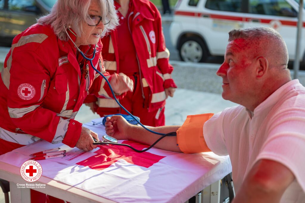 Un volontario della Croce Rossa misura la pressione arteriosa a un uomo presso lo stand informativo della Chiesa di San Michele a Pietralata.