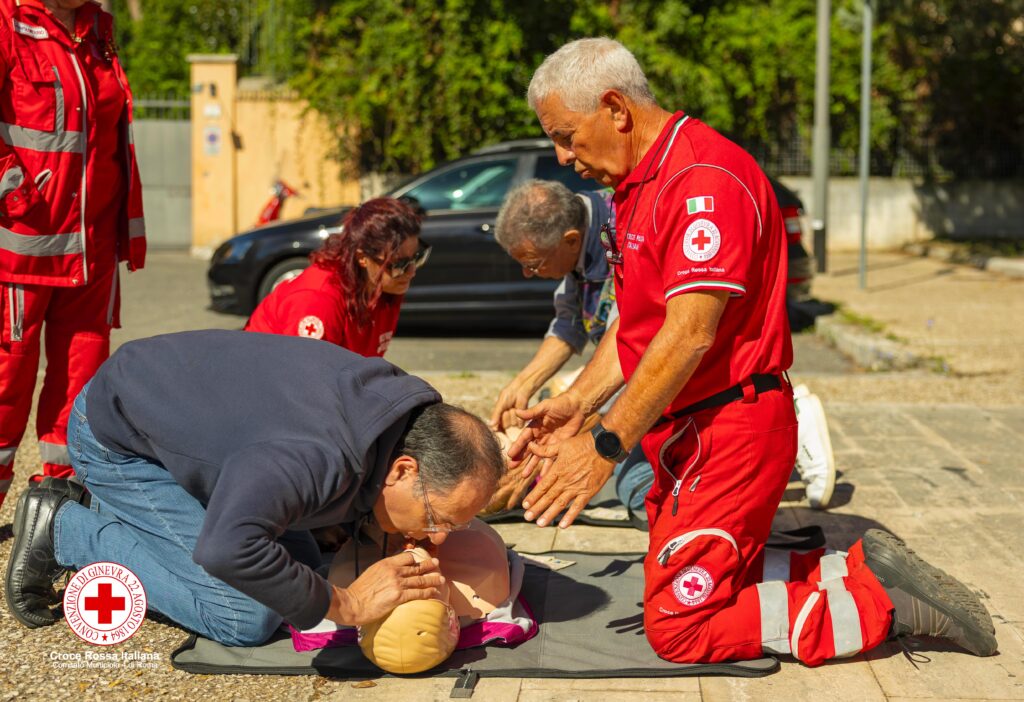 Dimostrazione pratica di rianimazione cardiopolmonare: un cittadino esegue la respirazione su un manichino guidato da un volontario CRI.